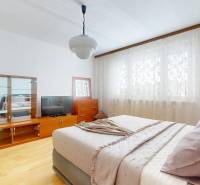 Schlafzimmer in einer 3-Zimmer-Wohnung mit Holzboden, Vorhängen und Möbeln.