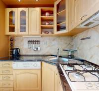 Küche in einer 3-Zimmer-Wohnung mit Spüle, Kochfeld und Holzschränken.