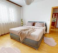 Helles Schlafzimmer mit großem Bett und Holzboden in einer 3-Zimmer-Wohnung.