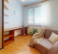 Ein Zimmer mit einem Tisch, einem Sessel und einem Boden mit Holzdekor in einer 3-Zimmer-Wohnung.