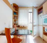 Küche mit Esstisch, Holzschränken und Fenster in einer 3-Zimmer-Wohnung.