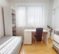 Ein Zimmer in einer 3-Zimmer-Wohnung mit einem Bett, einem Schreibtisch und einem Boden mit Holzdekor.