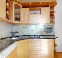 Küche mit Holzschränken und Arbeitsplatte, Holzboden in einer 3-Zimmer-Wohnung.