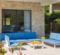 Außenbereich der Villa in Bale mit blauen Gartenmöbeln und einer Steinmauer.