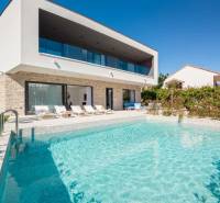 Eine Villa in Bale mit Pool und Liegestühlen, umgeben von Grün und blauem Himmel.