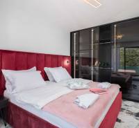 Schlafzimmer in der Villa mit einem Bett, das mit rotem Samt gepolstert ist, und einem Glasschrank.