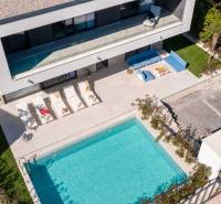 Eine Villa in Bale mit Pool, Liegestühlen und einer gemütlichen Außensitzgelegenheit.