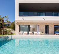 Villa in Bale mit Pool, Palmen, Terrasse und Liegestühlen im Hintergrund.