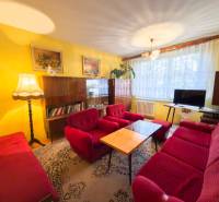 Wohnzimmer einer 3-Zimmer-Wohnung mit roten Sofas, Teppich, Wanddekorationen, Holzmöbeln.