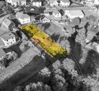 Baugrundstück in Turzovka, umgeben von Häusern, mit Grasbewuchs und Bäumen.