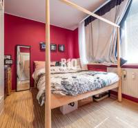 Schlafzimmer mit Bett, Spiegel und Holzboden in einer 4-Zimmer-Wohnung.
