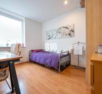 Schlafzimmer in einer 4-Zimmer-Wohnung mit Holzboden und violetter Tagesdecke.