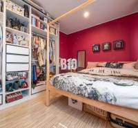 Schlafzimmer mit Bett, Holzboden und offenem Kleiderschrank in einer 4-Zimmer-Wohnung.