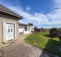 Ein Einfamilienhaus in Ondrejovce mit Hof, Brunnen und Blick auf die offene Landschaft.