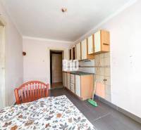 Küche mit einfachen Schränken, Fliesen und Tisch in einem Einfamilienhaus.