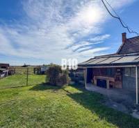 Ein Einfamilienhaus in Ondrejovce mit Garten, Unterstand und Blick auf die Natur bei sonnigem Wetter.