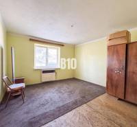 Einfaches Zimmer in einem Einfamilienhaus mit Teppichboden und Holzmöbeln.