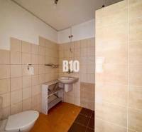 Ein Badezimmer in einem Einfamilienhaus mit beigen Fliesen und weißen Sanitäreinrichtungen.