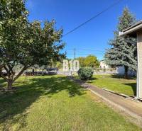 Ein Garten bei einem Einfamilienhaus in Ondrejovce mit Rasen, Bäumen und Sträuchern.