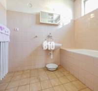 Ein Badezimmer in einem Einfamilienhaus mit einer Badewanne und hellen Fliesen an den Wänden.