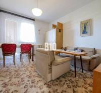 Wohnzimmer in einem Einfamilienhaus mit Teppich und roten Stühlen.