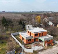 Ein im Bau befindliches Einfamilienhaus, umgeben von einem Garten, mit ländlichem Blick auf die Felder.