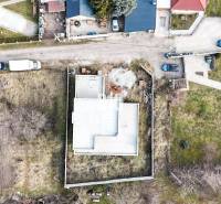 Ein im Bau befindliches Einfamilienhaus auf einem Grundstück, umgeben von einem Garten und benachbarten Häusern.