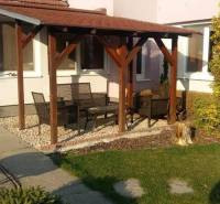 Ein Einfamilienhaus in Čierna Voda mit Terrasse, Gartenmöbeln und grünem Rasen.