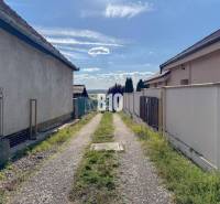 Ein schmaler Weg zwischen den Häusern im Gebiet Pozemky - Wohnen, Nitra, der zu einem Panoramablick auf die Landschaft führt.