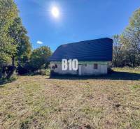 Eine Hütte in Lackov, umgeben von Natur, mit einem blauen Dach, sonniger Tag.