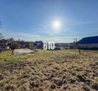 Ein Grundstück mit Betonfundament bereit zum Wohnen, sonniges Wetter und umliegende Landschaft.