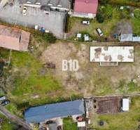 Luftaufnahme eines Grundstücks mit einem Gebäude und Parkplätzen, ideal zum Wohnen.