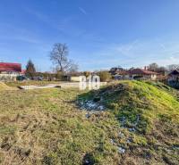 Baugrundstück, verschneites Gras, umgeben von Häusern und Dächern.