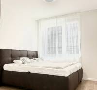 Schlafzimmer in einer 2-Zimmer-Wohnung mit Holzboden und einem bequemen Bett.