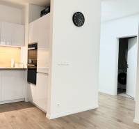 Küche in einer 2-Zimmer-Wohnung mit Holzboden und weißen Möbeln.