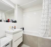 Badezimmer mit Badewanne und Vorhang in einer 2-Zimmer-Wohnung, weißer Schrank und Wäschekorb.