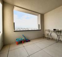 Ein Balkon mit Blick auf die Stadt, mit Spielzeug und Möbeln in einer 2-Zimmer-Wohnung.