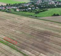 Landwirtschaftliche und forstwirtschaftliche Flächen bei Nová Ves nad Váhom mit einem Dorf im Hintergrund.