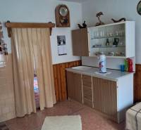 Innenraum eines Einfamilienhauses mit einfacher Küche, Boden mit Holzdekor und Vorhängen.