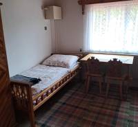 Ein Zimmer in einem Einfamilienhaus mit einem Bett, einem Fenster, einem Tisch und Stühlen.