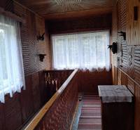 Holzinterieur eines Einfamilienhauses mit dekorativem Geländer und Teppichen im Flur.