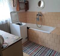 Badezimmer in einem Einfamilienhaus mit Waschmaschine, Badewanne und Spiegel an der Wand.