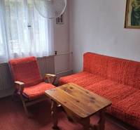 Ein Zimmer in einem Einfamilienhaus mit roten Sesseln, einem Tisch und Vorhängen mit Gardinen.