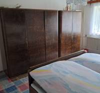 Schlafzimmer im Einfamilienhaus mit Bett, Schränken und Teppich mit buntem Muster.