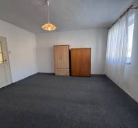 Izba s kobercovou podlahou, bielymi stenami, dvoma skriňami a veľkým oknom.