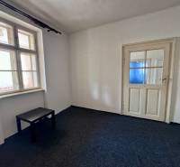 Izba s tmavým stolíkom, oknom a bielymi dverami v rodinnom dome.