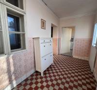 Ein Flur in einem Einfamilienhaus mit gefliestem Boden und weißen Möbeln.