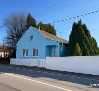 Blaues Familienhaus in Kunovo, Senica, an der Hauptstraße, umgeben von grünen Bäumen.