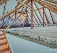 Ein Dachboden in einem Einfamilienhaus mit sichtbaren Holzbalken und einer Treppe.