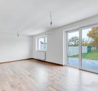 Ein Interieur in einem Einfamilienhaus mit einem Boden in Holzoptik und großen Fenstern.
